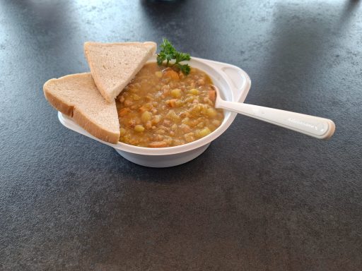 Linsensuppe mit zwei Brotscheiben und frischer Petersilie als Garnitur.